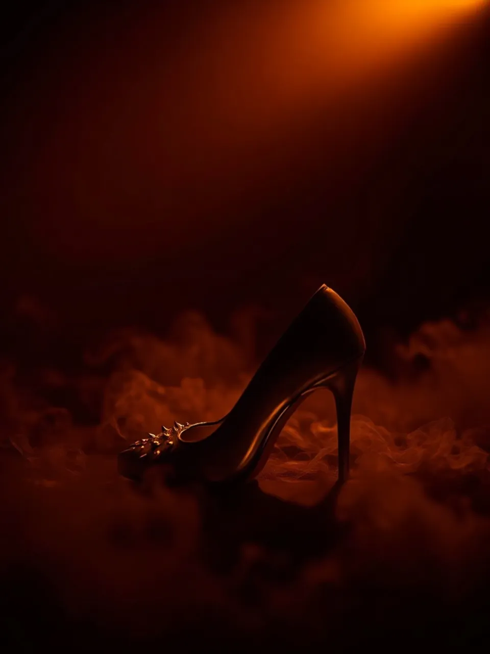 Single spiked stiletto on its side, amber-lit smoke